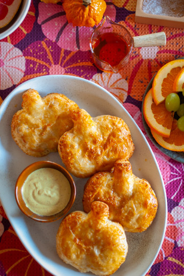 Pumpkin-shaped frittata hot pockets served with Dijon aioli on a white tray.