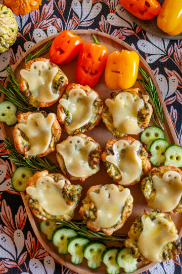 Spinach and artichoke dip in puff pastry cups topped with Provolone cheese ghosts.
