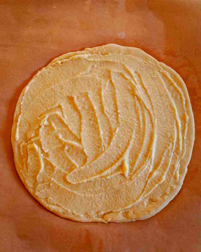 One circle of sweet dough with frangipane spread evenly over it. 