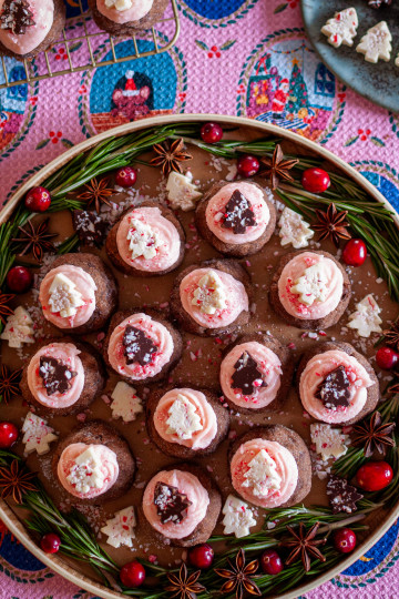 Peppermint bark chocolate truffle cookies with oink peppermint buttercream froting and tree-shaped peppermint bark on top.