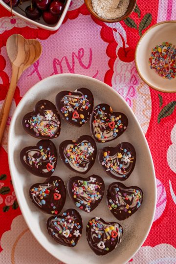 Medjool date peanut butter cups with colorful sprinkles, on a white platter.