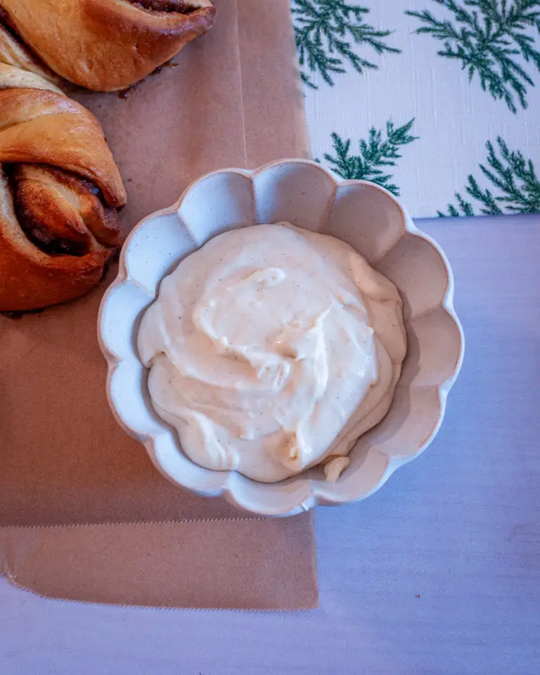 Spiced cream cheese frosting in a scalloped bowl.